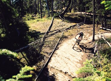 Man biking on a trail in the forest. A\J AlternativesJournal.ca